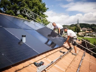 Arbeiter installieren eine Solaranlage auf einem Eigenheim. 